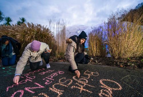 Teachers writing in chalk on the paths in front of Eden's Biomes